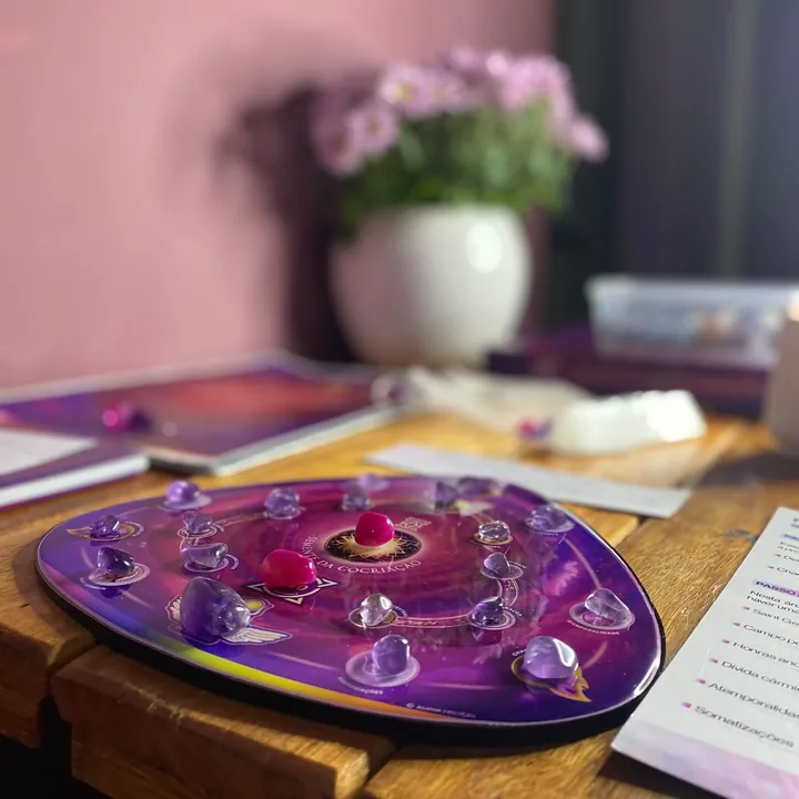 A mesa radiônica Semente da Cocriação posta sobre uma mesa de madeira, com cristais nos pontos